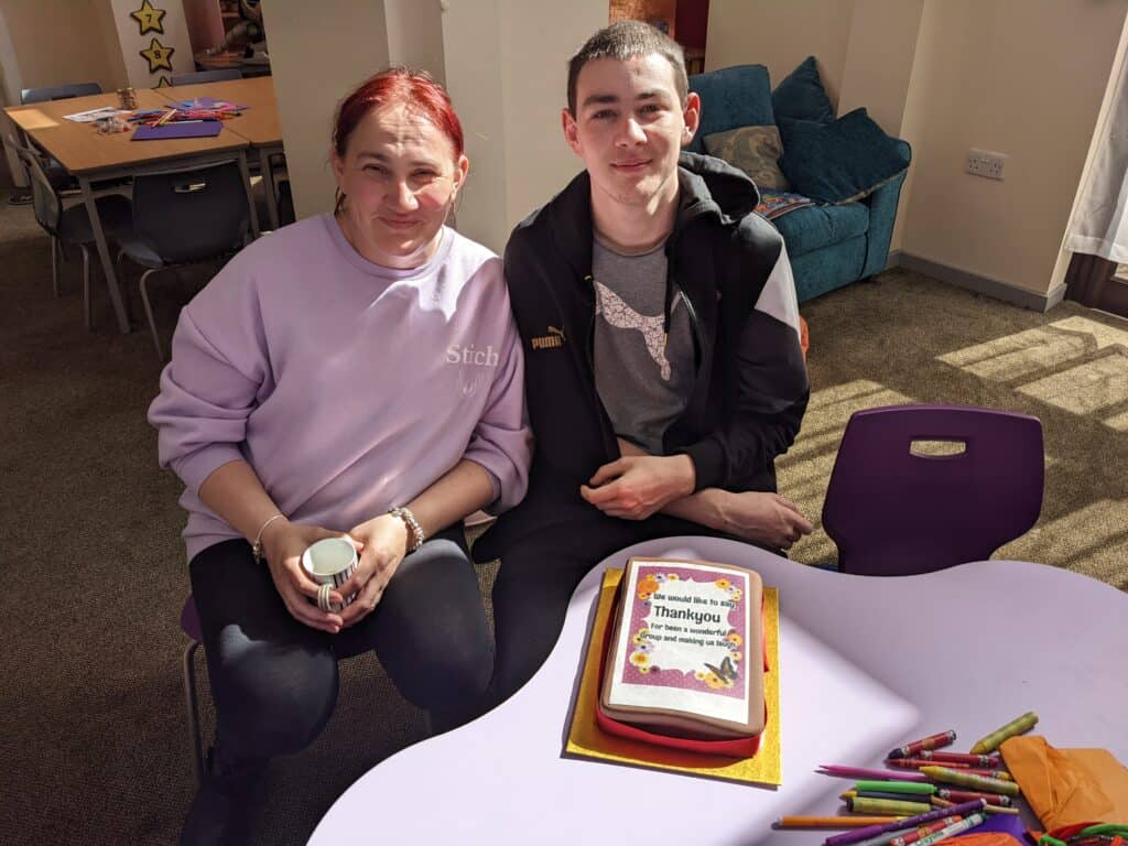 Two people posing for a photo by a cake